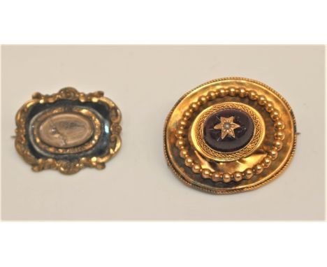 An early Victorian mourning brooch, gilt metal mount, the centre with a glass panel enclosing hair, black surround and scroll
