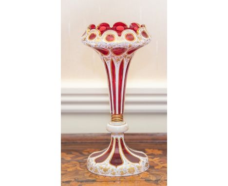 A Bohemian ruby and overlay glass vase, circa 1890, the drawn trumpet form rising to an onion-shaped top with lobed rim, the 