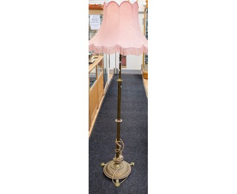 A late Victorian/Edwardian brass telescopic standard lamp, with floret centre knop, the domed base raised on three shell feet