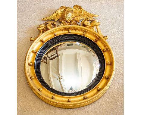A Regency style giltwood, gesso and parcel ebonised convex wall mirror, the circular plate within an ebonised reeded surround