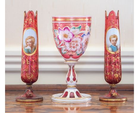 A pair of Bohemian ruby glass and overlay stem vases, circa 1880-90, of slender ovoid form, overlaid with white oval panels p