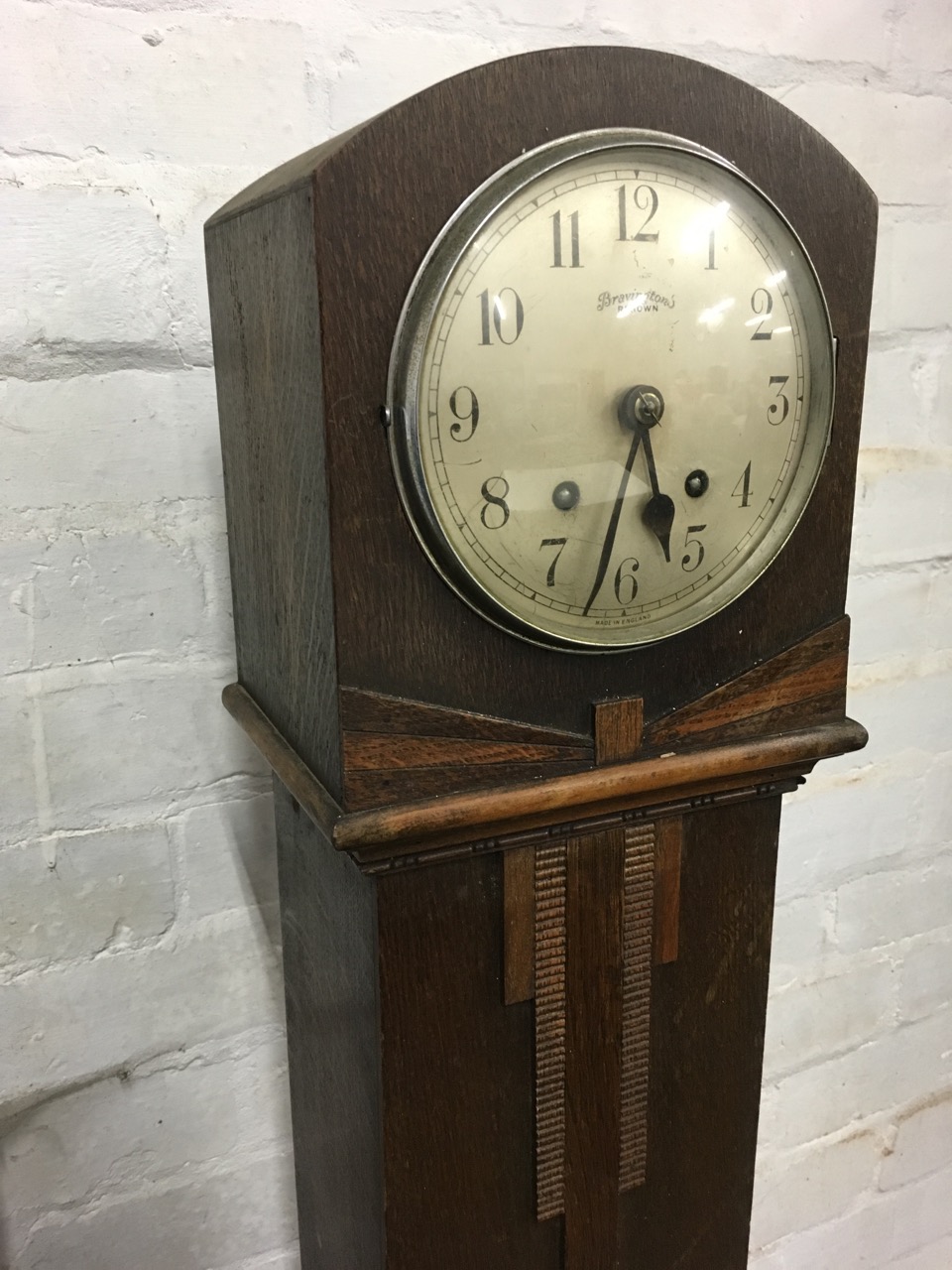 A deco oak cased grandmother clock, the Bravingtons Ltd silvered dial under convex glass in domed