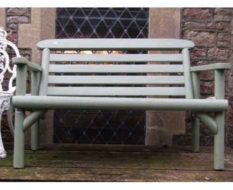 A rustic two seat garden bench with slatted seat and back and light green painted finish