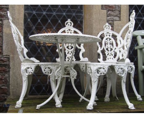 A cream painted Victorian style cast aluminium garden terrace table of circular form with pierced top and swept tripod suppor