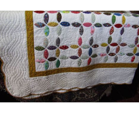 A vintage hand stitched quilt decorated with patchwork type floral panels upon a white ground.