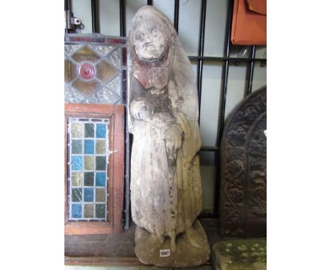 An early carved limestone niche figure of an elderly woman wearing a pleated skirt and hooded shawl aided by a rustic walking