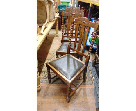 A set of four Edwardian oak dining chairs with bobbin moulded backs and forelegs, shaped splats and drop in seats