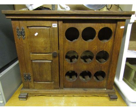 A low oak side cupboard with panelled frame, the front elevation partially enclosed by a twin fielded panelled door flanked b