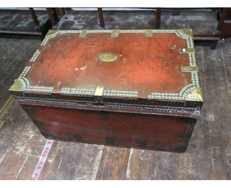A George III travelling trunk with original crimson leather panels, the overlay with polished brass stud work and bands, the 