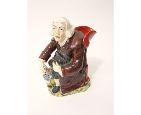 A 19th century Staffordshire George Whitfield type Toby jug in the form of a seated preacher in brown great coat, holding a b