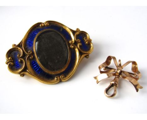 A gold bow brooch with attached 15ct clasp, together with a yellow metal mourning brooch with scrolling border to a blue enam