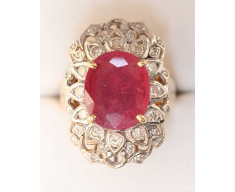 An 18ct gold, diamond and ruby cluster ring, set with large ruby measuring 13.5 x 11mm, surrounded by diamonds in an elaborat