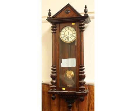 A Victorian walnut Vienna wall clock, with cream enamel dial and black Roman numerals, with turned columns and triangular ped