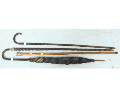 A silver topped walking stick, two other sticks and an umbrella. (4)