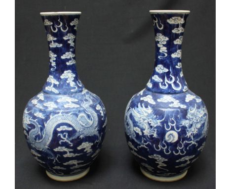 A pair of late 19th century Chinese blue and white bottle vases, decorated with four clawed dragons chasing a pearl, against 
