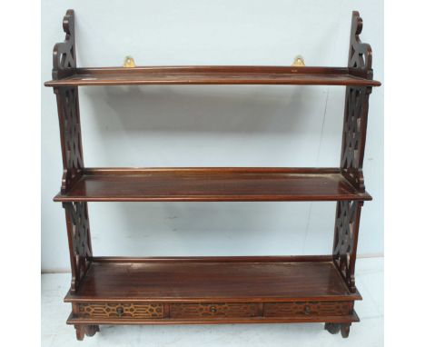 A Chippendale style carved hardwood triple wall shelf, with lattice work sides and three small drawers.