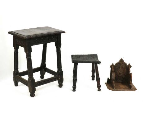 A carved oak stool,the concave seat with stylised foliate decoration, on four turned legs, the underside of the seat inscribe