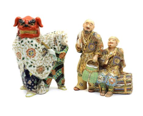 A Japanese Satsuma ware group,20th century, of a brushwood gatherer seated on a large tied bundle of brushwood, another figur
