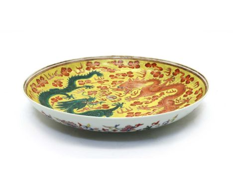 A Chinese porcelain plate,of circular form, painted with two dragons chasing a flaming pearl against a yellow ground, the und