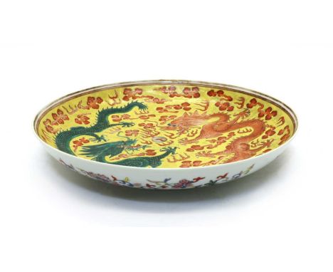 A Chinese porcelain plate,of circular form, painted with two dragons chasing a flaming pearl against a yellow ground, the und