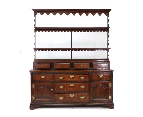 An oak dresser,18th century and later adapted, with a three-tier rack, four fixed open drawers, over an arrangement of drawer