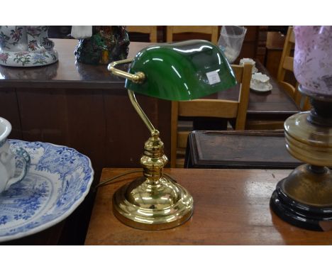 A brass desk light with green glass shade
