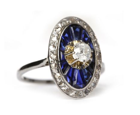 ART DECO SAPPHIRE AND DIAMOND RINGof oval form, with a central old cut cushion shaped diamond of approximately 0.32 carats, s