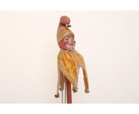 Papier-mache Punch on stick, circa 1900, with exaggerated painted features, original yellow and peach costume with bells and 