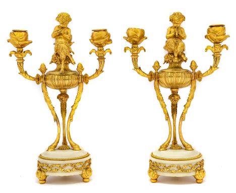 {} A Pair of French Gilt Metal and White Marble Three-Branch Candelabra, 19th century, each surmounted by a figure of Pan sit