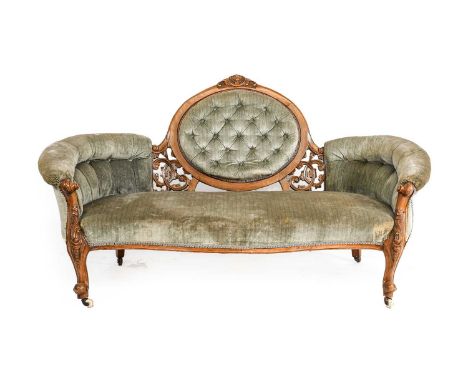 ~  A Victorian Walnut-Framed Sofa, circa 1865, recovered in buttoned green velvet, with overstuffed back support above a serp