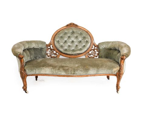 ~  A Victorian Walnut-Framed Sofa, circa 1865, recovered in buttoned green velvet, with overstuffed back support above a serp