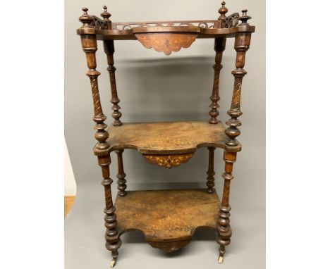 A decorative 19th century three tier what not with serpentine inlaid shelves, turned legs to ceramic castors, gallery and fin