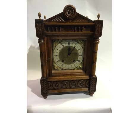 A late 19th century German chiming Carved oak bracket clock. Pineapple finials above brass dial with matted centre, silvered 
