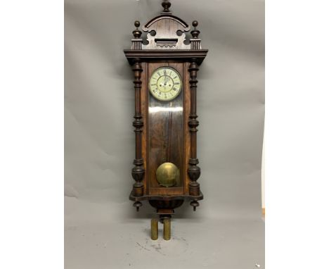 A large mahogany Vienna style wall clock. Enamel face with Roman numeral markers. 136cm(h)