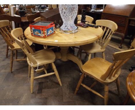 Circular pine kitchen table on tripod foot and set of six flat back kitchen chairs 