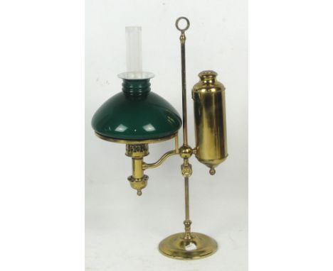 A brass rise and fall lamp oil table lamp with cylindrical reservoir, loop handle and green shade, height 53cm.