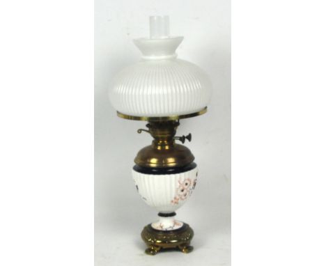 A late Victorian brass oil lamp with porcelain fluted urn shaped reservoir and with white opaque glass shade, height 60cm inc