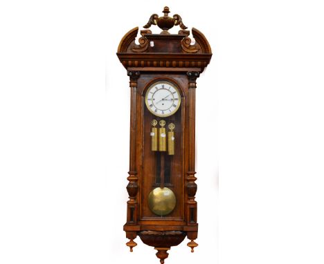 A late 19th century Vienna Grand Sonnerie three weight wall clock with urn set arched pediment above white enamel dial set wi