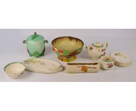 A quantity of Clarice Cliff items, comprising a floral and foliate decorated biscuit barrel, a footed bowl, a log shaped vase