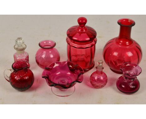 A small collection of cranberry tinted glass including a decanter lacking stopper, small jug, jar and cover, etc.