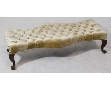 A Victorian walnut button upholstered shaped stool of serpentine outline raised on knee carved cabriole legs to scrolling fee