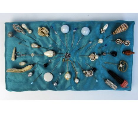 A large collection of vintage hatpins including horn, diamante, and pearl bead examples, an example in the form of a fox's he