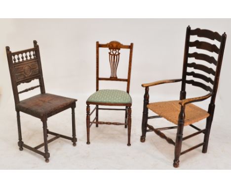 A ladder back rush seated elbow chair, an inlaid and upholstered bedroom chair, and a further carved example (3).