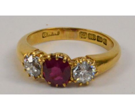 An 18ct gold ruby and diamond three stone ring, the central ruby weighing approximately 0.65cts flanked by two diamonds weigh