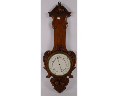 A 1920s oak cased aneroid barometer with foliate decorative scrolls, height 81cm (lacking thermometer).