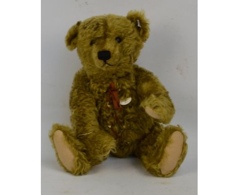 A boxed Steiff teddy bear with hot water bottle no.406621, with numbered white and black tag to ear, with curly brass coloure