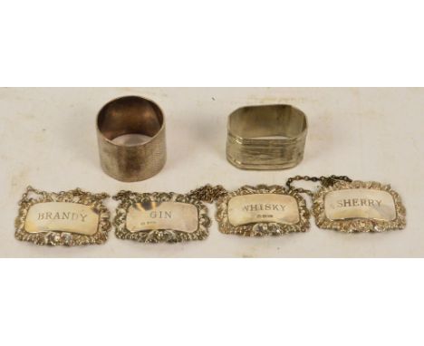 Three modern silver bottle labels; gin, whisky and brandy, a hallmarked silver circular napkin ring, a plated napkin ring and