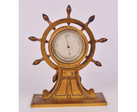 An early 20th century gilt metal barometer in the form of a ship's wheel, the circular gauge housing a semi-circular mercury 