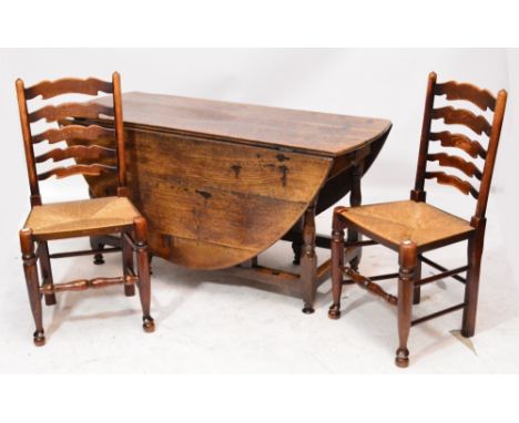 An antique oak oval gateleg table with two end drawers, width 140cm, and a set of four ladder back rush seated chairs (5).