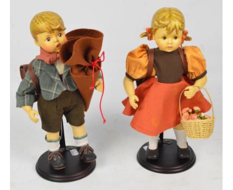 A pair of boy and girl Goebel & Hummel dolls with bisque heads and limbs, and dressed in Austrian clothing with school bags, 